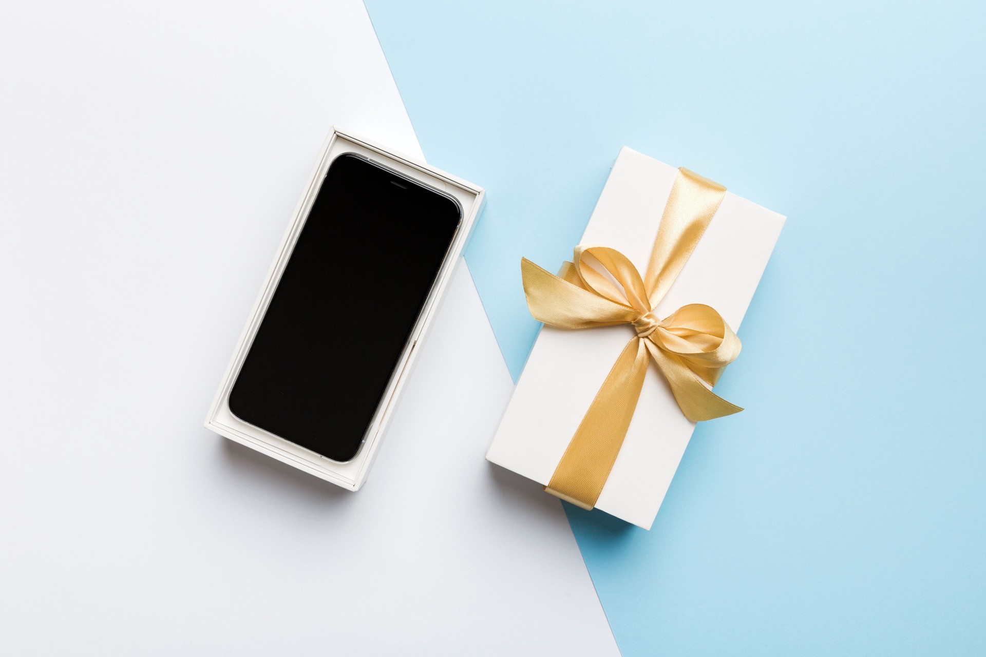 Opened gift box with gold ribbon and smartphone on color background, top view. Blank open box packaging mockup , Template for your design - branding mockup